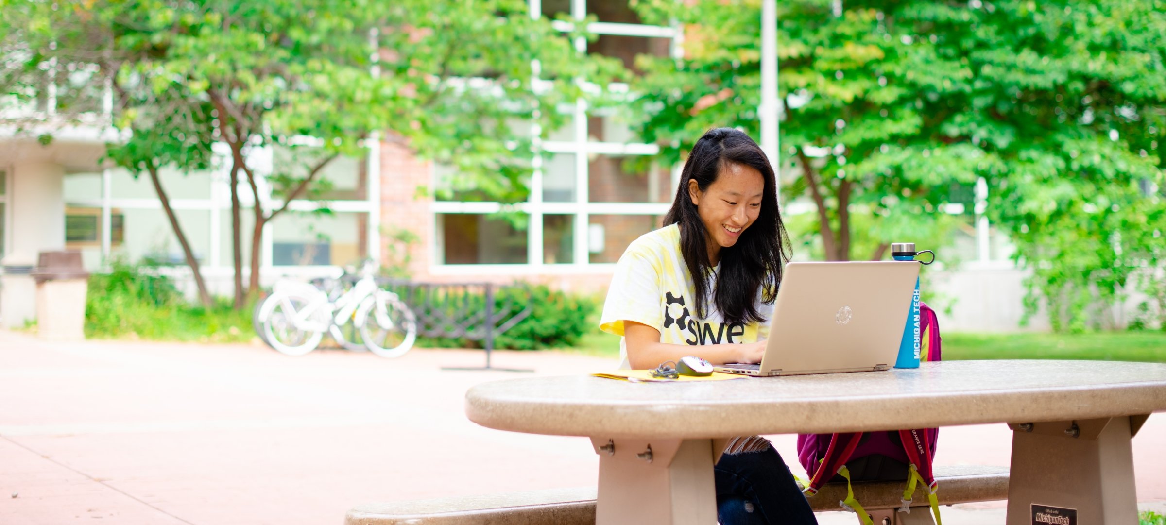 Michigan Tech student studies with a laptop outside on a picnic table.