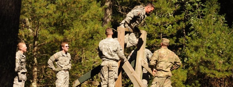 Cadets outside on the Confidence Course, one climbing a wooden structure
