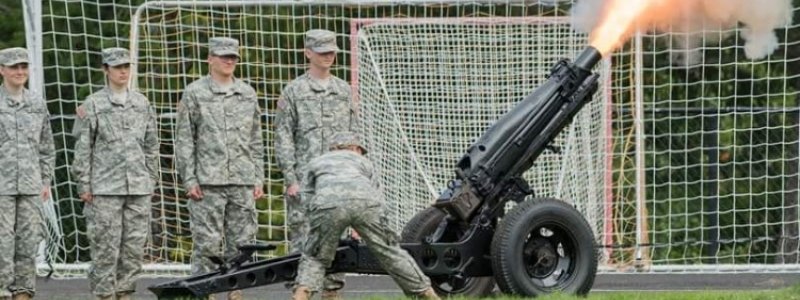 Cadets lined up with one firing the Howitzer cannon