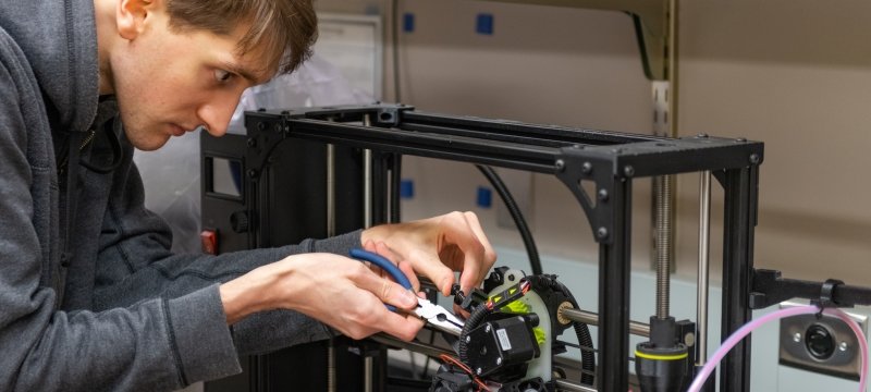 Student working on a 3D printer in a teaching lab.