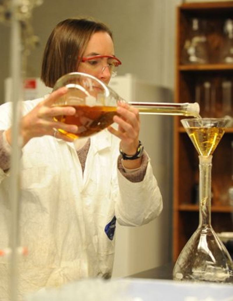 A girl pourig chemicals in a lab coat 