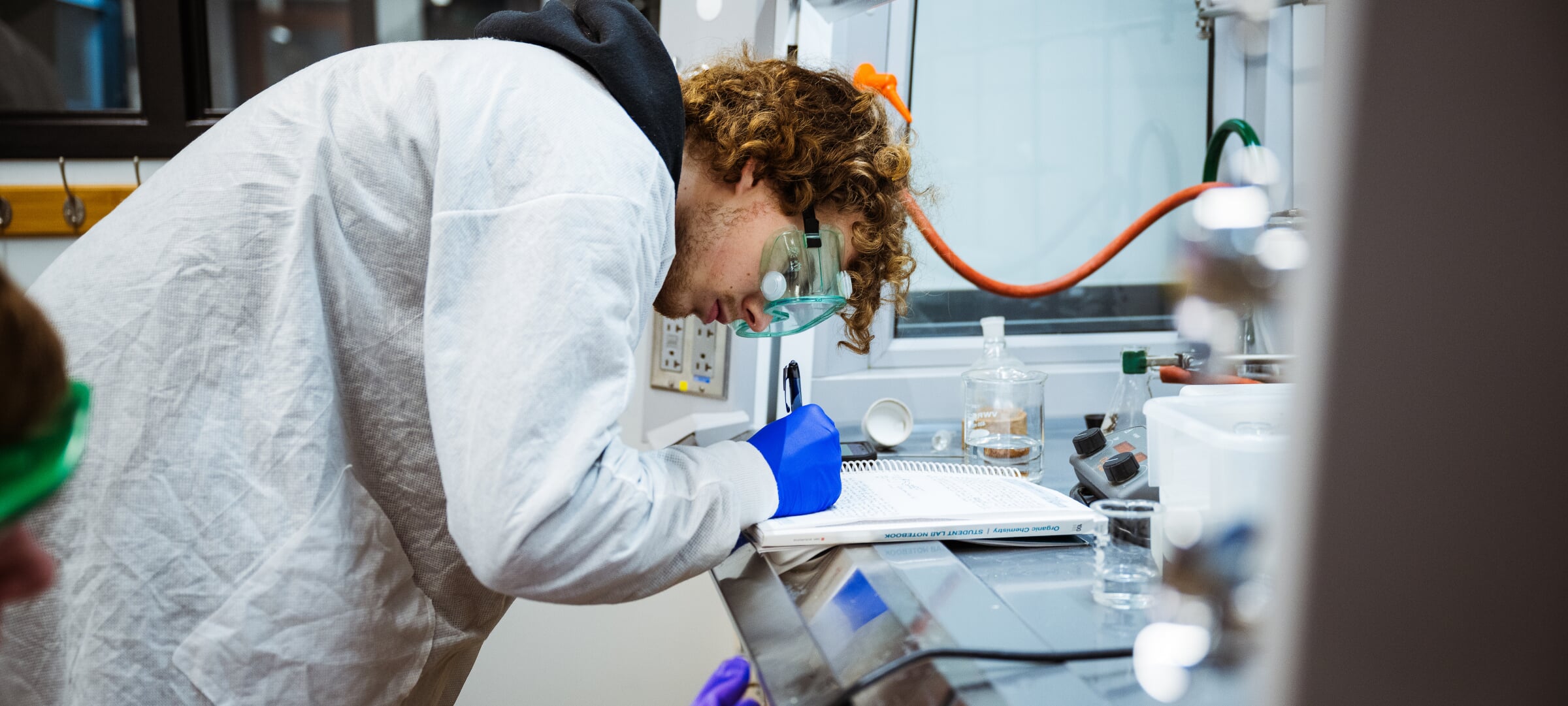 A student taking notes wearing personnel protection equipment