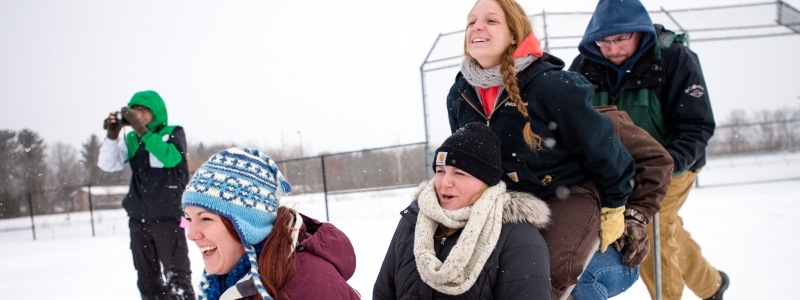 Alumni on a dog sled at the baseball field during Winter Carnival