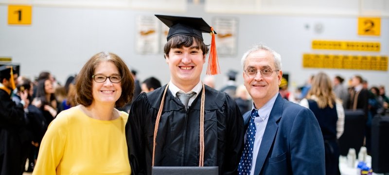 A new graduate and his parents at midyear commencement.