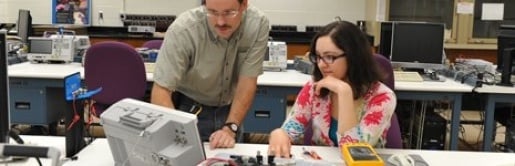 A professor showing a student a piece of lab equipment. 