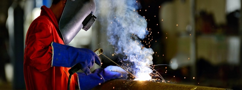 Welder using proper safety equipment to cut through metal.