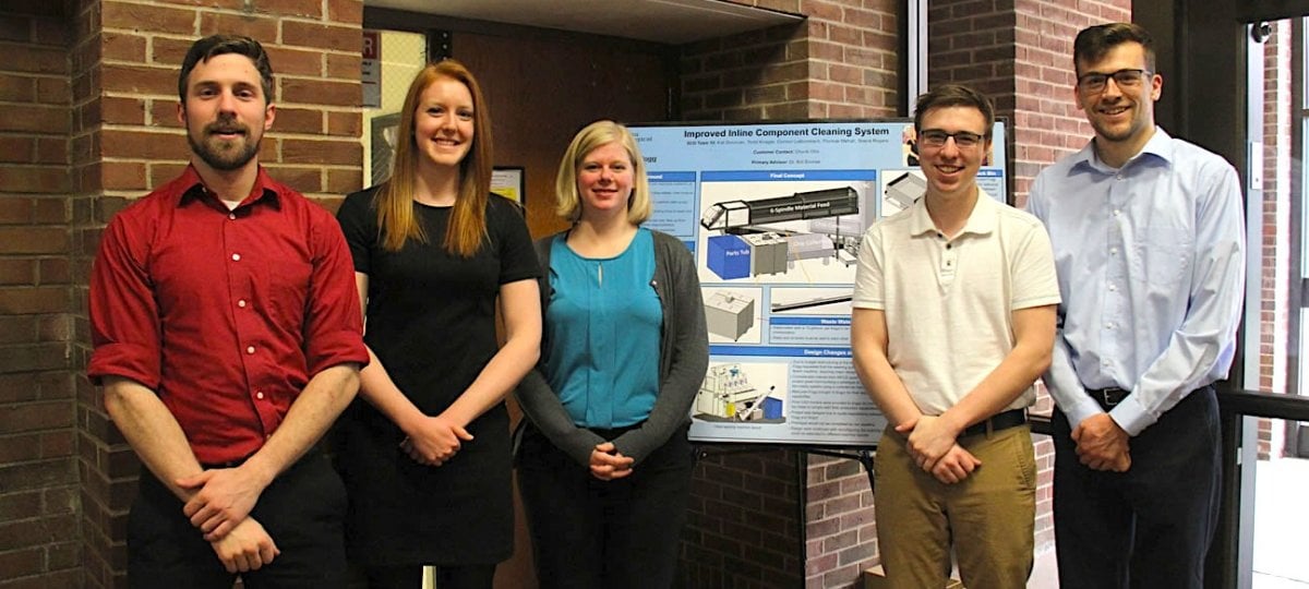 Five seniors stand next to their project poster.