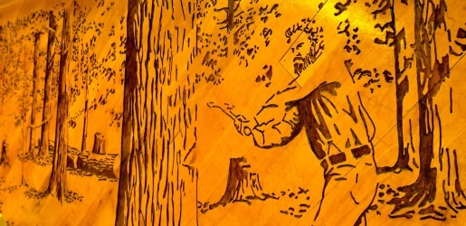 Wood mural of logger chopping down a tree.