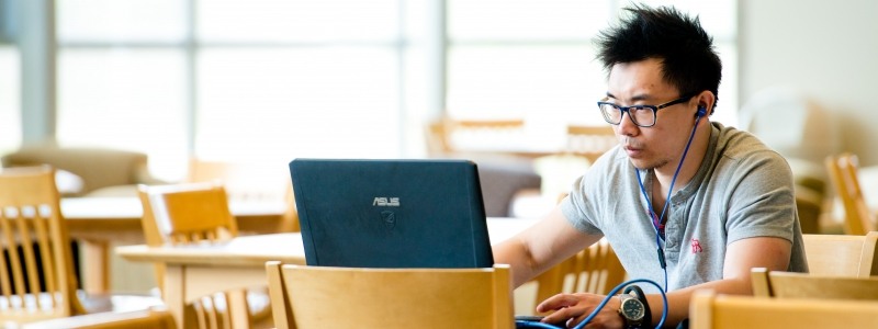 student in bright library studying at computer