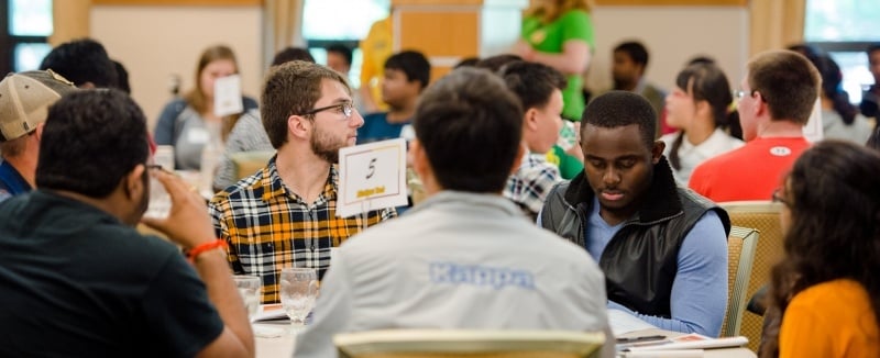 Graduate students meet around a table at orientation.