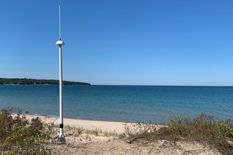 Radar antenna in the sand next to the lake.