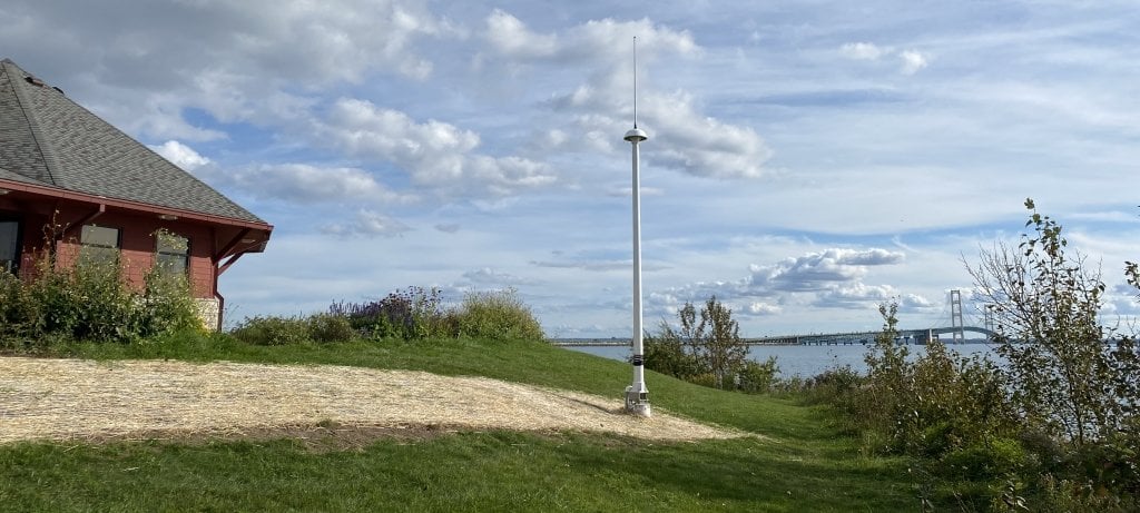 Straits of Mackinac - Northern High Frequency Radar on a hill next to a building with the straits and bridge in the background.