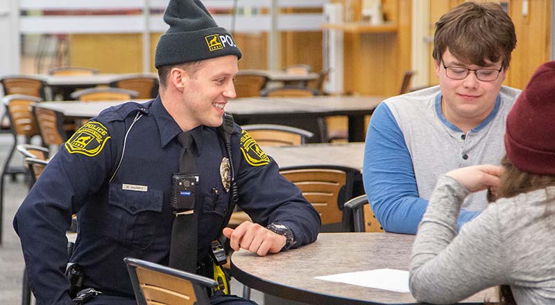 MTU public safety officer smiling while sitting with students