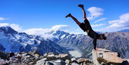Student doing a handstand on a rock, high in the mountains.