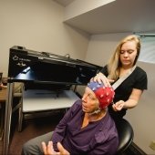 Student researcher fitting a brain monitoring cap on an elderly person's head
