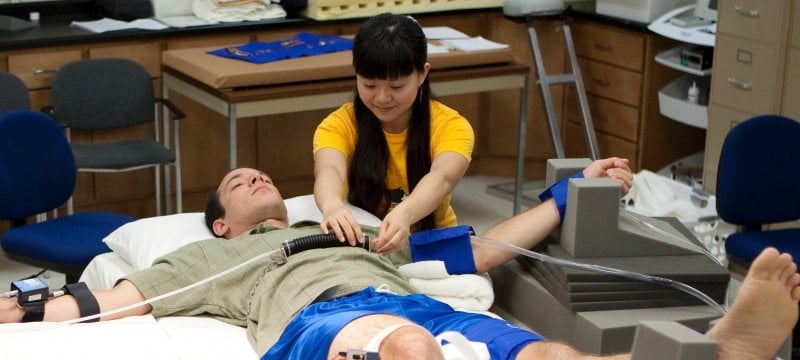 Researcher fixing a device onto a participant laying down.
