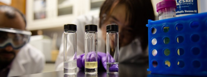 Researchers looking a vials of liquid in a lab.