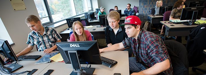 Students working in groups at computers in an instruction room.