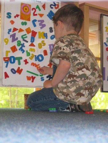 Child plahying with magnetic letters and numbers on a board.