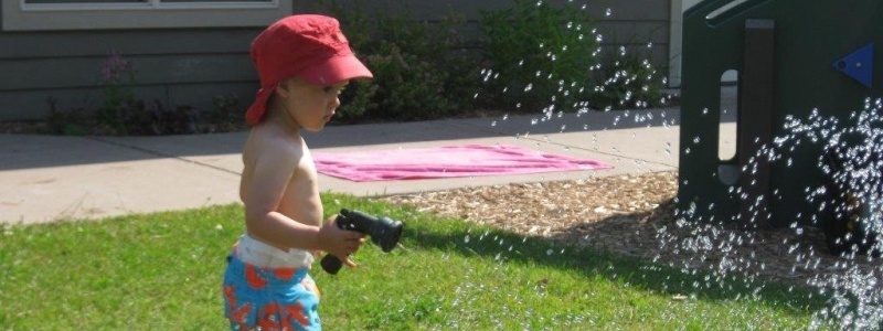 Child playing outside in a sprinkler.