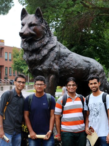Four international students in front of the husky statue.