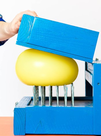Balloon being pressed onto a bed of nails.
