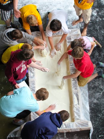 Overhead image of students playing in a tub of oobleck.
