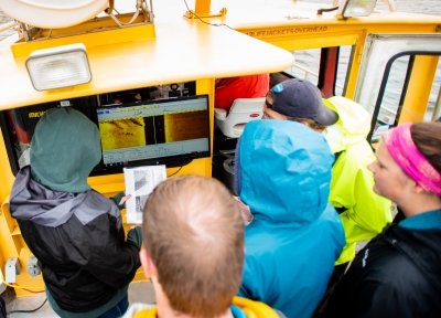 People looking at a sonar screen on a boat.