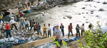 Community members move rocks to build the center pier of the bridge across the Rio Montagua. Image Credit: Mike Paddock