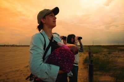 Kristin Brzeski holds her baby while others look out with binoculars.