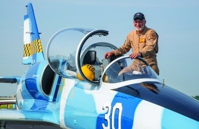 Ron Staley getting into the cockpit of a blue and white jet.