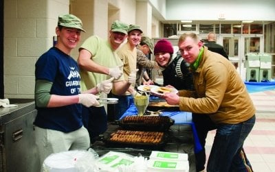 Cadets serving pancakes and sausage to students.