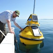 Researcher reaching for a buoy in the water.