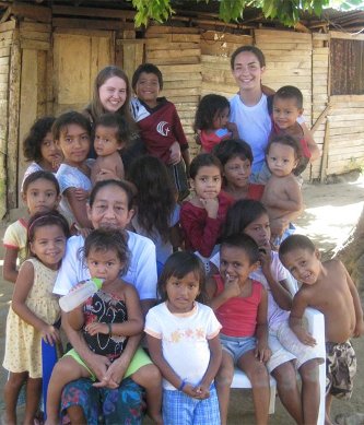 Ashley (Thode) Julien '10, left, and Esther Johnson '09 standing behind Honduran children and a woman from the community where they had hoped to build a school. <em>Photo: Ashley Maes</em>