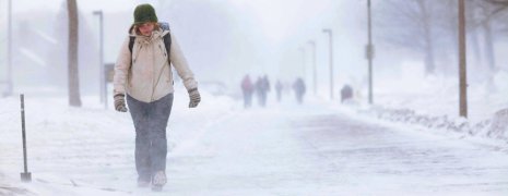 Student walking on campus in the snow.