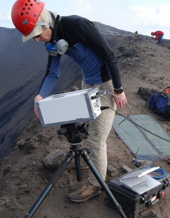 Researcher setting up equipment at a volcano site.