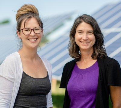 Chelsea Schelly and Richelle Winkler standing in front of a row of solar panels.