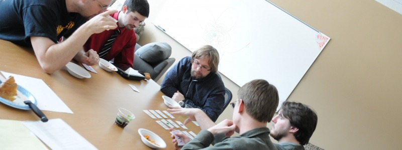 Graduate students discussing card strategy around a table