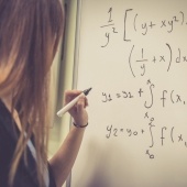 Woman writing out math equations on a whiteboard.