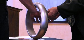 An engineer places their hand through a steel ring to receive the Order of the Engineer.