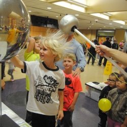 Students hair sticking up while touching a Van de Graaff generator.