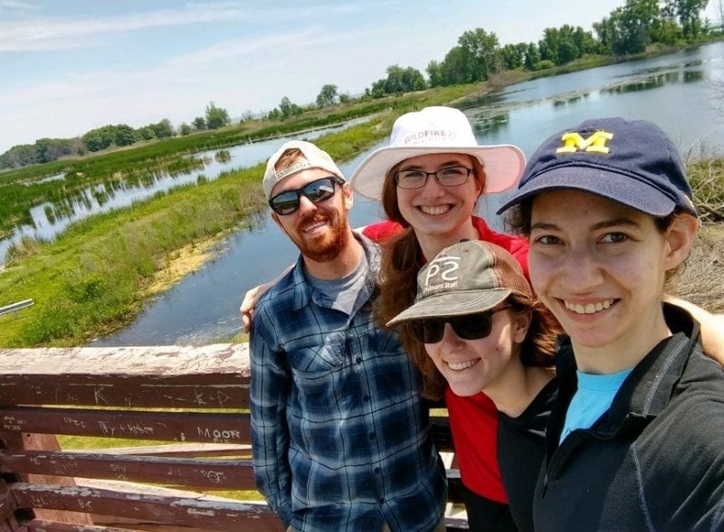 Four interns on a deck with wetlands in the background.