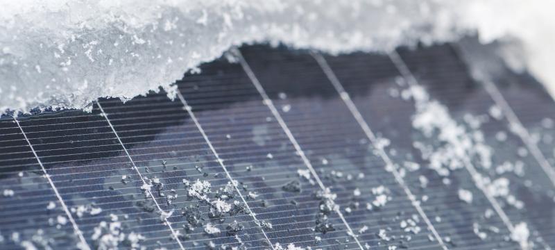 A solar panel with snow on the edges.