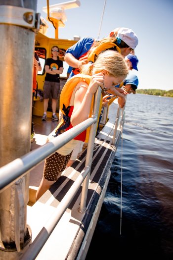 Students watch a Secchi disk dropped over the side of the R/V Agassiz to measure the water clarity. 