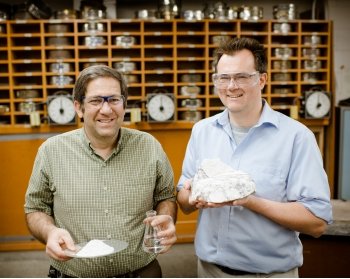 Two men stand next to each other holding gypsum and plaster of Paris.