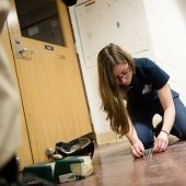 A young woman sets up the screws and bolts on a floor in a hall