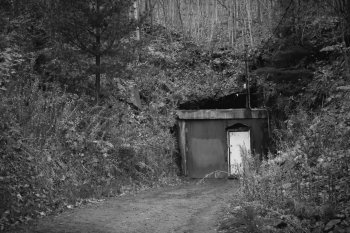 The door to Quincy Mine set into a hillside in a black and white photo with the doors closed. 