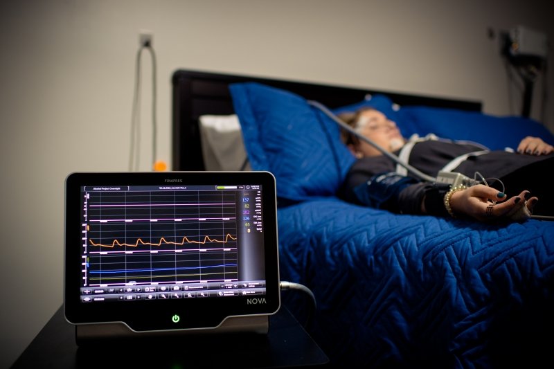 person sleeping on a bed behind a tablet with a medical display