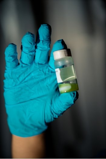 gloved hand holding plastic vial