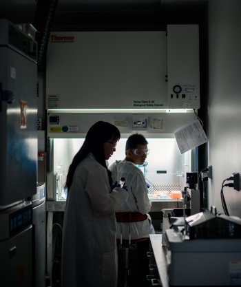 people in labs backlit next to a chemical exhaust hood